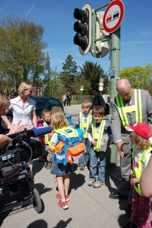 Deshalb verabschiedet der Herr Minister die Kinder und lässt sie mit ihrer „Fahrerin mit Kinderwagen“, die sie jeden Tag begleitet, weiter nach Hause „fahren“.