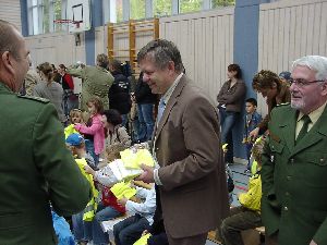 und schon geht es an die Arbeit: Die Ehrengäste verteilen die Sicherheitswesten des ADAC an die Kinder (hier: Staatssekretär Freller und Polizeipräsident Junker)