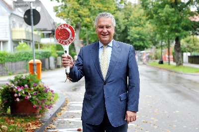 Staatsminister Joachim Herrmann erinnert mit der Winkerkelle „Halt Kinder“ die Autofahrer daran, dass sie besonders vorsichtig fahren und auf die Kinder achten